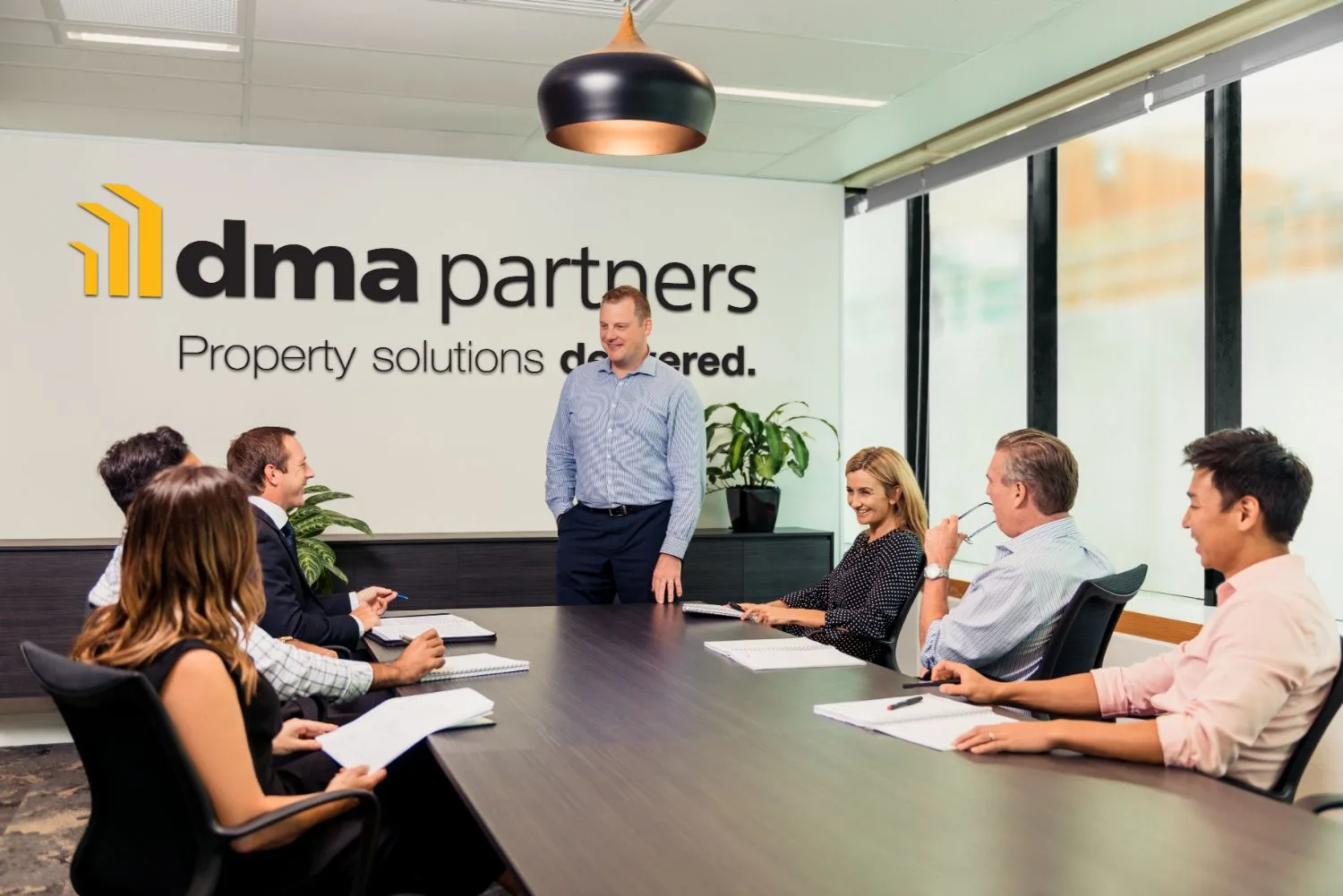 Team meeting in a boardroom in front of the dma partners office branding