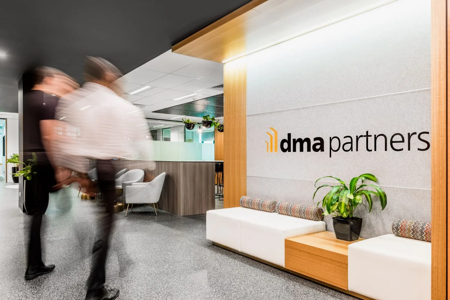 Office reception with company signage and staff moving through the space
