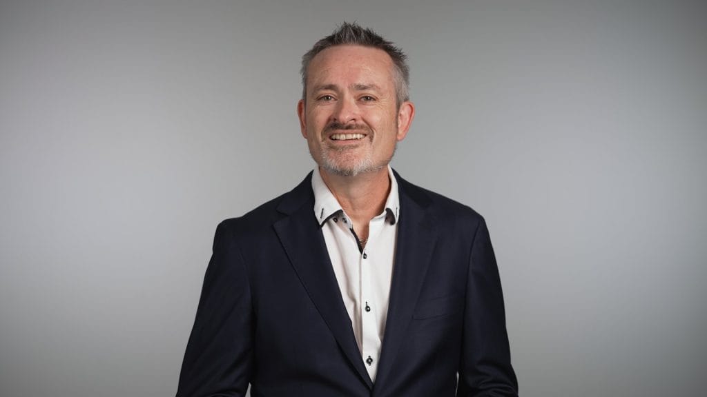 Smiling middle-aged man in suit, studio background.