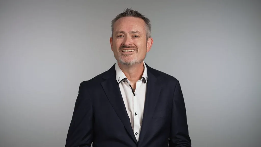 Smiling middle-aged man in suit, studio background.
